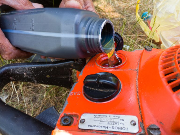 Worker pour oil in oil tank for chain lubrication of old used petrol chainsaw